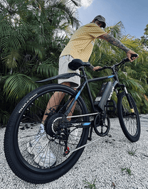 Uomo alla guida della mountain bike elettrica VARUN M24-1 in colore nero su una strada sterrata