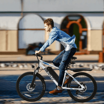 Uomo alla guida della mountain bike elettrica VARUN M24-1 in colore bianco in città