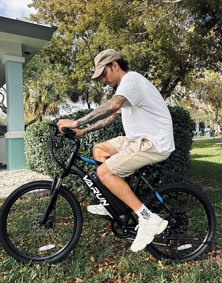Uomo alla guida della mountain bike elettrica VARUN M24-1 in colore nero in un parco