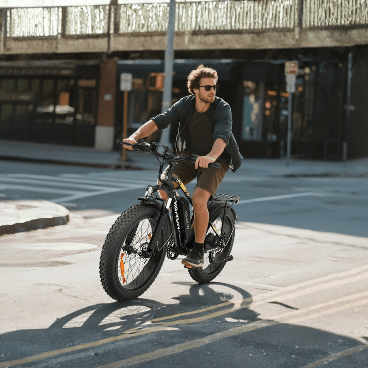 Uomo alla guida della fat bike elettrica VARUN M26-2 Plus in colore nero in una strada