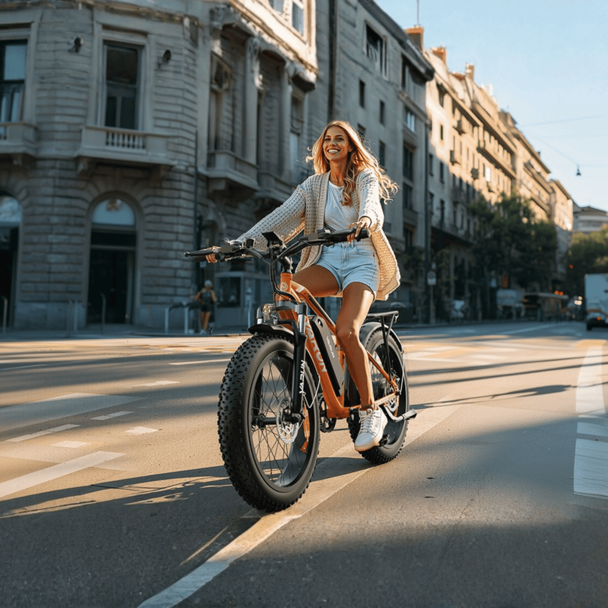 Donna alla guida della fat bike elettrica VARUN M26-2 Plus in colore arancione in città