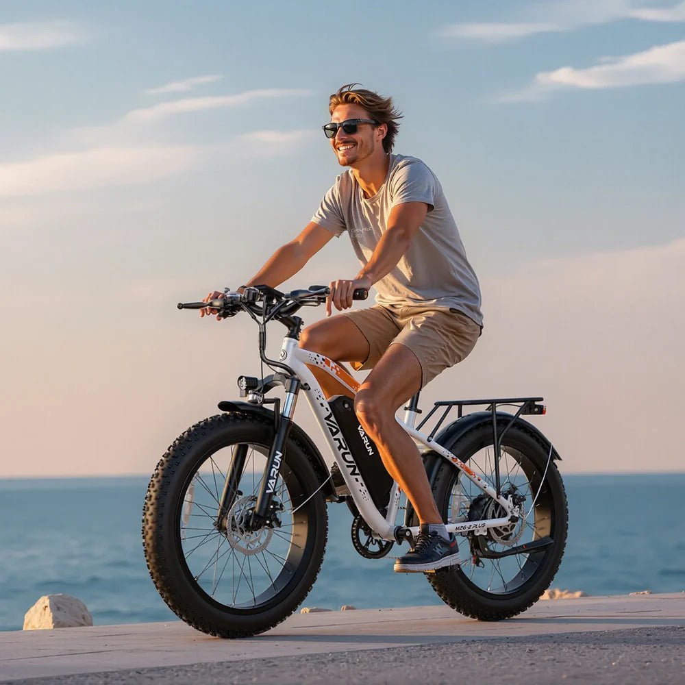 Uomo alla guida della fat bike elettrica VARUN M26-2 Plus in colore bianco in riva al mare