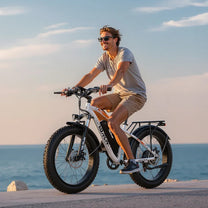 Uomo alla guida della fat bike elettrica VARUN M26-2 Plus in colore bianco in riva al mare
