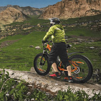 Pilota con la fat bike elettrica VARUN M26-2 Pro in fuoristrada con il casco in montagna