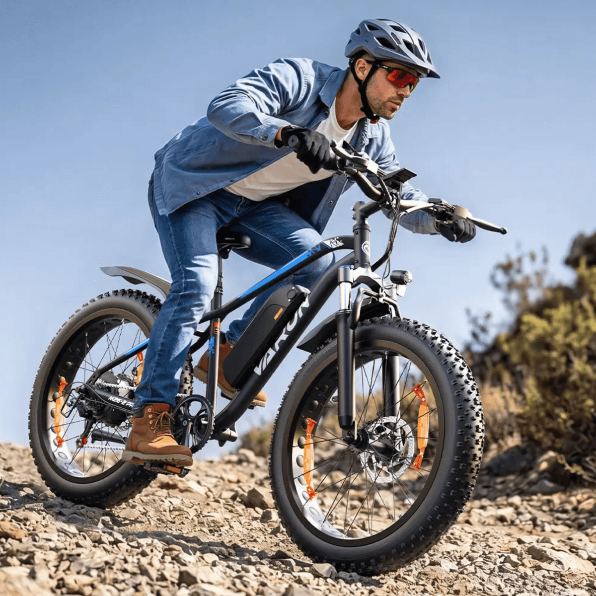 Uomo alla guida della fat bike elettrica VARUN M26-2 Pro in colore nero con il casco su un sentiero
