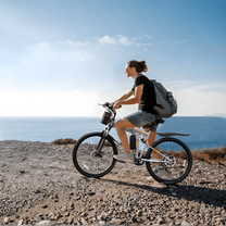 Persona alla guida della mountain bike elettrica VARUN M26-3 Pro in colore nero in riva al mare