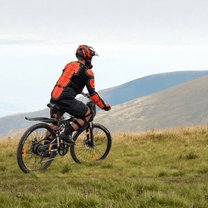 Uomo alla guida della mountain bike elettrica VARUN M26-3 Pro in colore nero con il casco in montagna