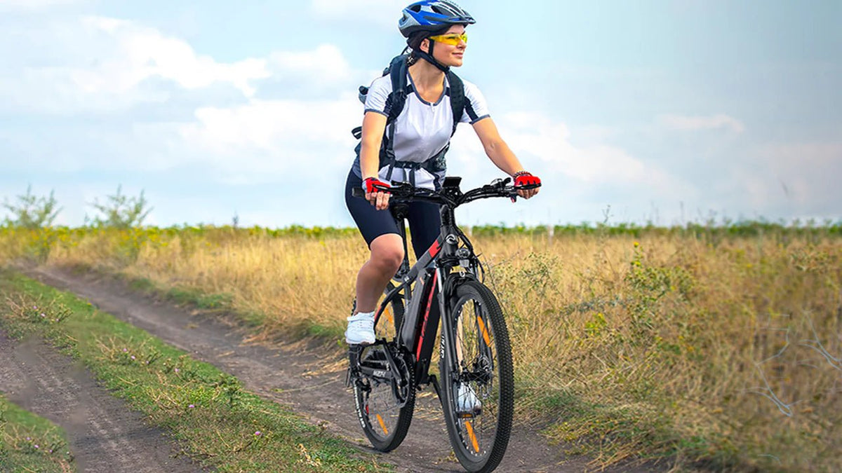 Donna alla guida della mountain bike elettrica VARUN M27-1 Pro con il casco su un prato