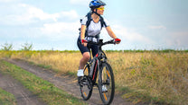 Donna alla guida della mountain bike elettrica VARUN M27-1 Pro con il casco su un prato