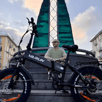 Uomo in piedi con la fat bike elettrica pieghevole VARUN S20-1 in colore nero in città