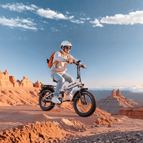 Pilota che salta con la fat bike elettrica pieghevole VARUN S20-1 Plus con il casco nel deserto