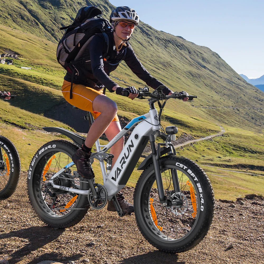Uomo alla guida della fat bike elettrica VARUN S26-1 in colore bianco con il casco in montagna