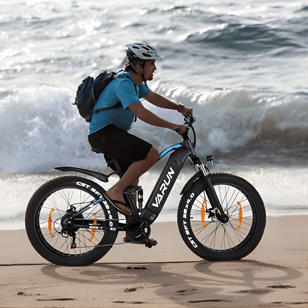 Uomo alla guida della fat bike elettrica VARUN S26-1 in colore bianco in riva al mare