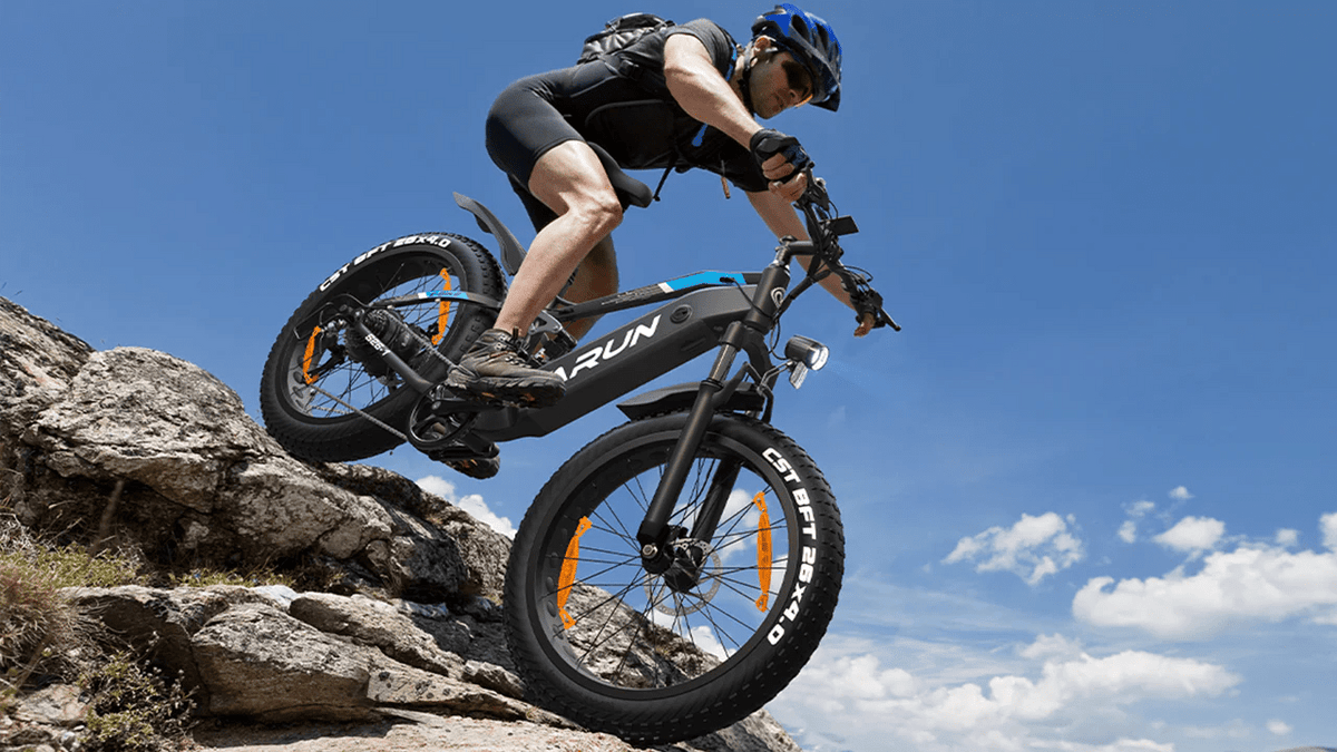 Pilota che salta con la fat bike elettrica VARUN S26-1 con il casco in montagna