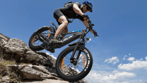 Pilota che salta con la fat bike elettrica VARUN S26-1 con il casco in montagna