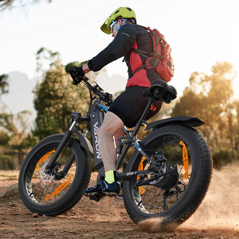 Uomo alla guida della fat bike elettrica VARUN S26-1 in colore nero con il casco su un sentiero