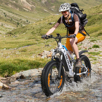 Pilota con la fat bike elettrica VARUN S26-1 in fuoristrada con il casco su un prato