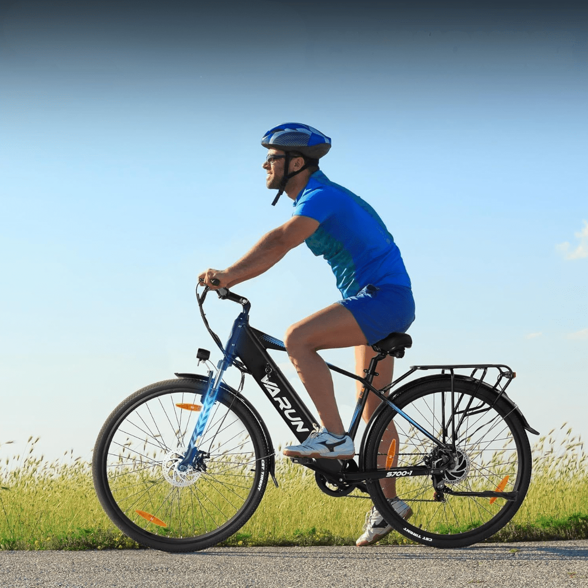 Uomo alla guida della bici elettrica VARUN S700-1 in colore nero con il casco su un prato
