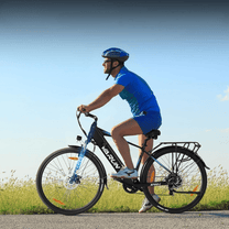 Uomo alla guida della bici elettrica VARUN S700-1 in colore nero con il casco su un prato