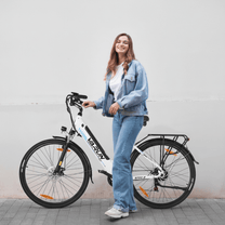 Donna in piedi con la bici elettrica VARUN S700-2 in colore bianco su sfondo bianco