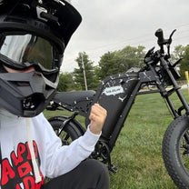 Uomo in piedi con la fat bike elettrica VARUN X-Plorer Raptor con il casco in un parco