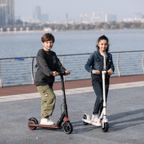 Bambino in piedi accanto al monopattino elettrico per bambini Wheely Junior S3